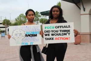 Two FGCU students hold signs during the protest on Thursday, Oct. 27. (EN Photo / Travis Brown)