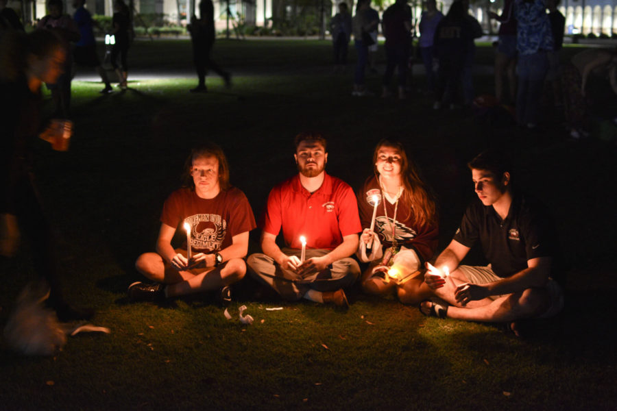 (EN Photo / Christian Rehm) Jordan Moses, left, and three others sit on the library lawn with candles in hand.  Moses gave a personal testimony of what he went through during the vigil.
